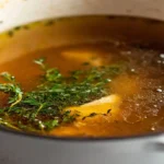 Homemade chicken broth simmering on the stove.